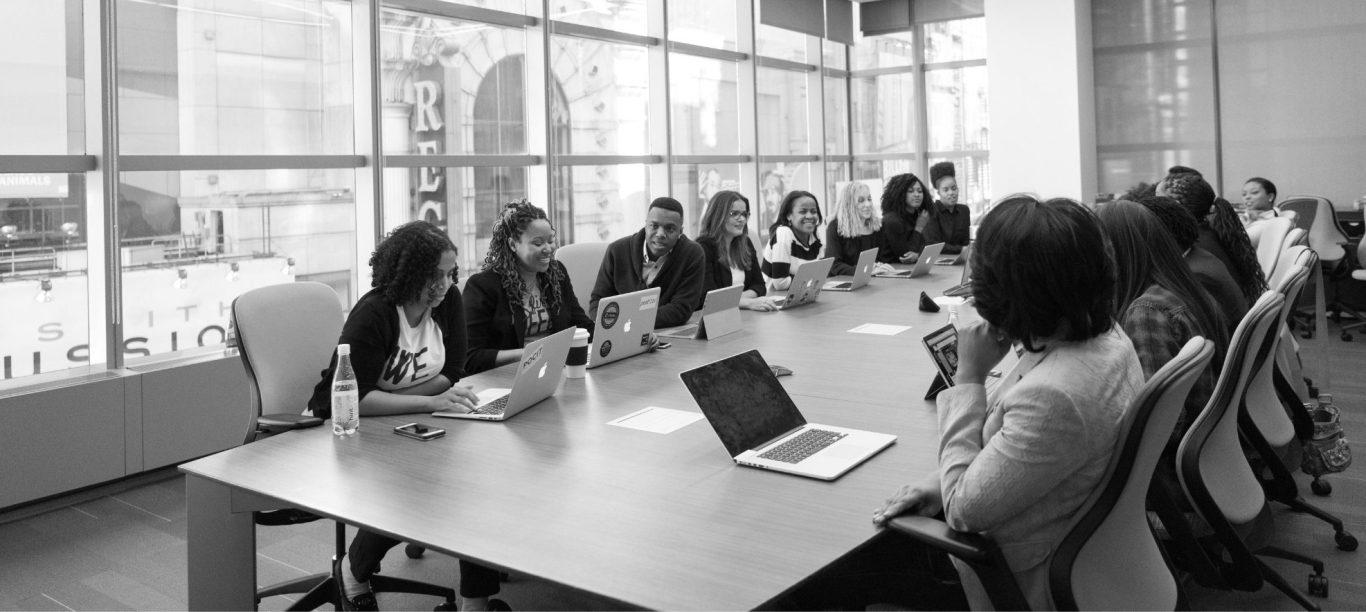 modalités et méthodes d'accompagnement Réunion professionnelle autour d'une grande table avec des participants en discussion.